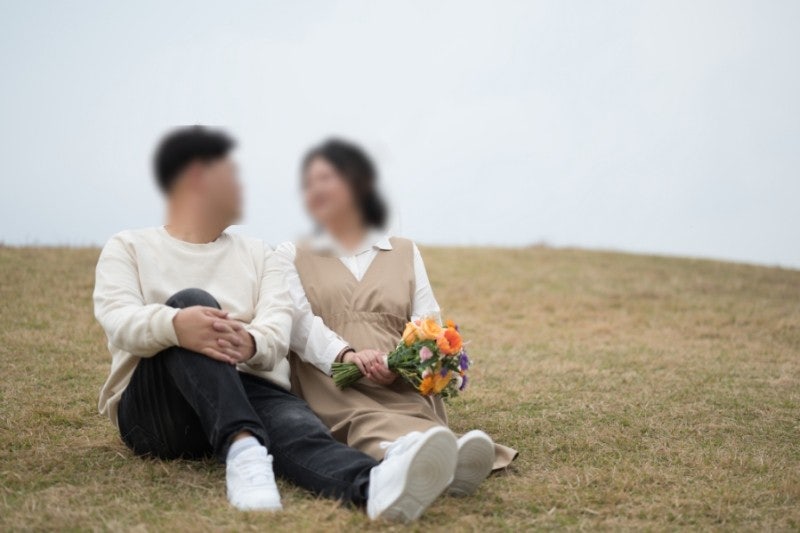 올림픽공원 언덕 잔디에 앉아 니트와 베이지 원피스로 톤을 맞춘 데이트스냅이에요. 풀밭에 편하게 앉는 포즈 참고용이에요.
