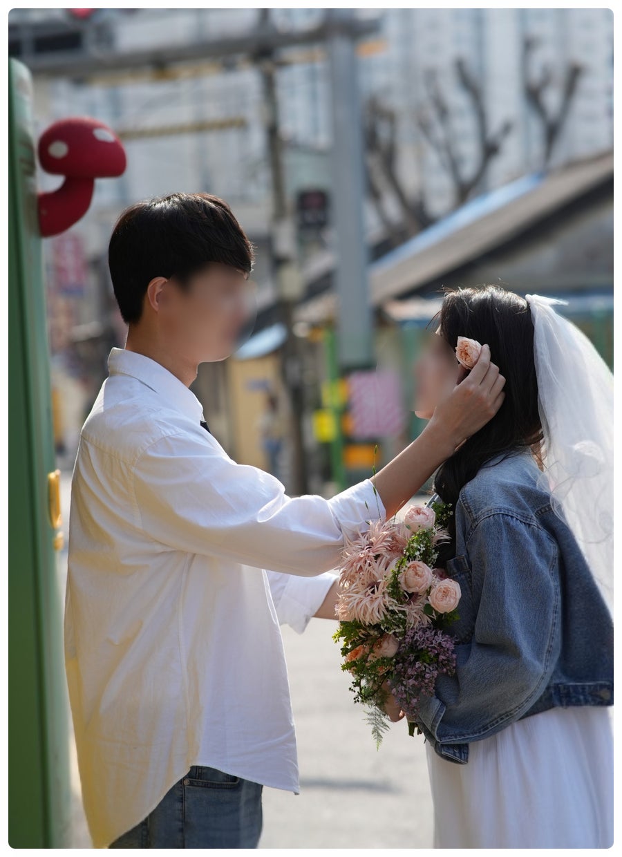 흰 셔츠·청바지 신랑이 청자켓에 베일을 쓴 신부의 머리를 넘겨주는 캐주얼 웨딩스냅이에요. 베일과 부케만 얹어 웨딩 느낌을 낸 방식이 세미 웨딩룩과 같아요.