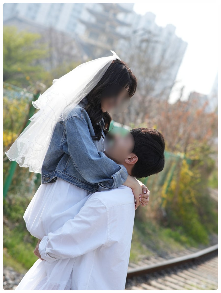 백빈건널목 철길 옆에서 청자켓 신부를 안아 올린 컷이에요. 베일이 바람에 날리는 순간이 필름 사진 같아요.
