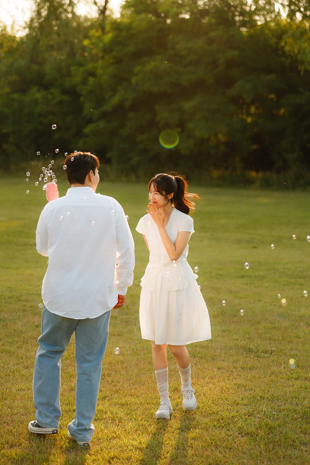 노을공원 잔디에서 비눗방울을 날리며 걷는 뒷모습이에요. 흰 셔츠에 청바지, 흰 원피스에 흰 양말·운동화를 맞춘 룩이에요.